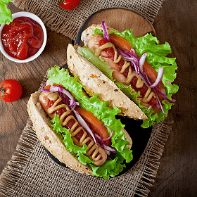 Two loaded classic hot dogs with mustard, lettuce, tomato, and onion