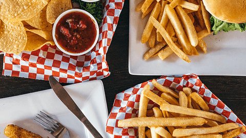 Loaded fries, salsa, chips and a burger on a checkered tray