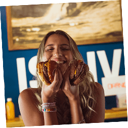 A woman happily eating a loaded sandwich