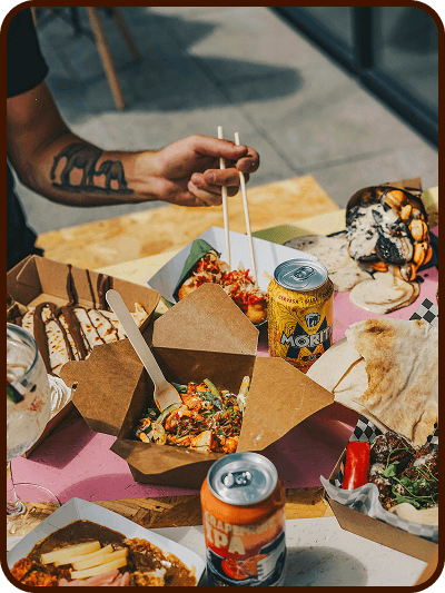 Hands grabbing pizza slices and fried chicken at a table