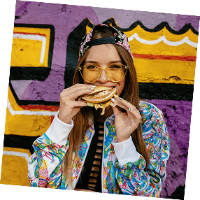A woman enjoying a wrap in front of a graffiti wall