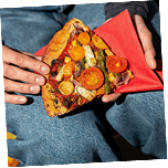 Hands holding a loaded slice of pizza